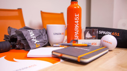 Photo of Spark451 branded mug, notebook, bottles, and more